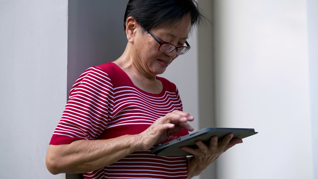 快乐退休女士，60岁，用触控板设备上网。视频素材