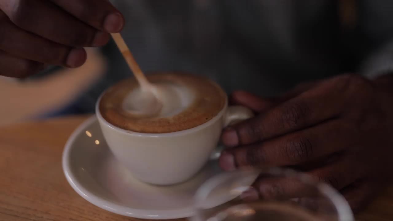 近距离拍摄非洲男子混合牛奶喝咖啡视频下载