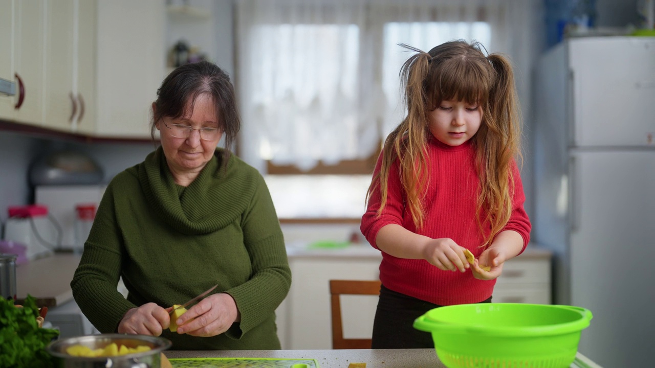 祖母和孙女在厨房里一起做饭。祖母教孙女健康饮食和可持续发展视频下载