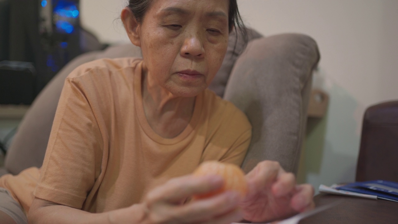 吃橙子的亚洲老年妇女。视频下载