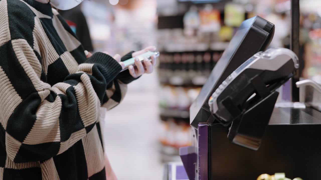 一位女士在超市收银员处扫描一张支票上的二维码视频下载