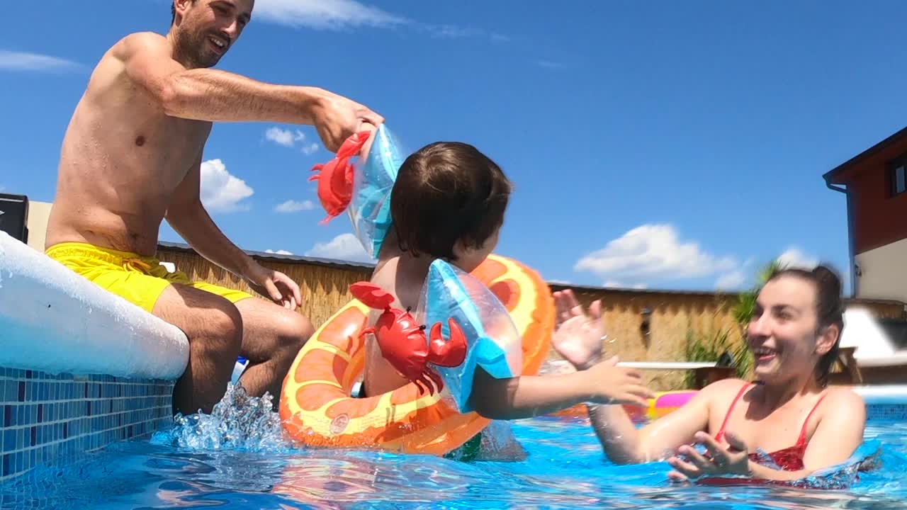 年轻的一家人在游泳池里玩得很开心视频素材