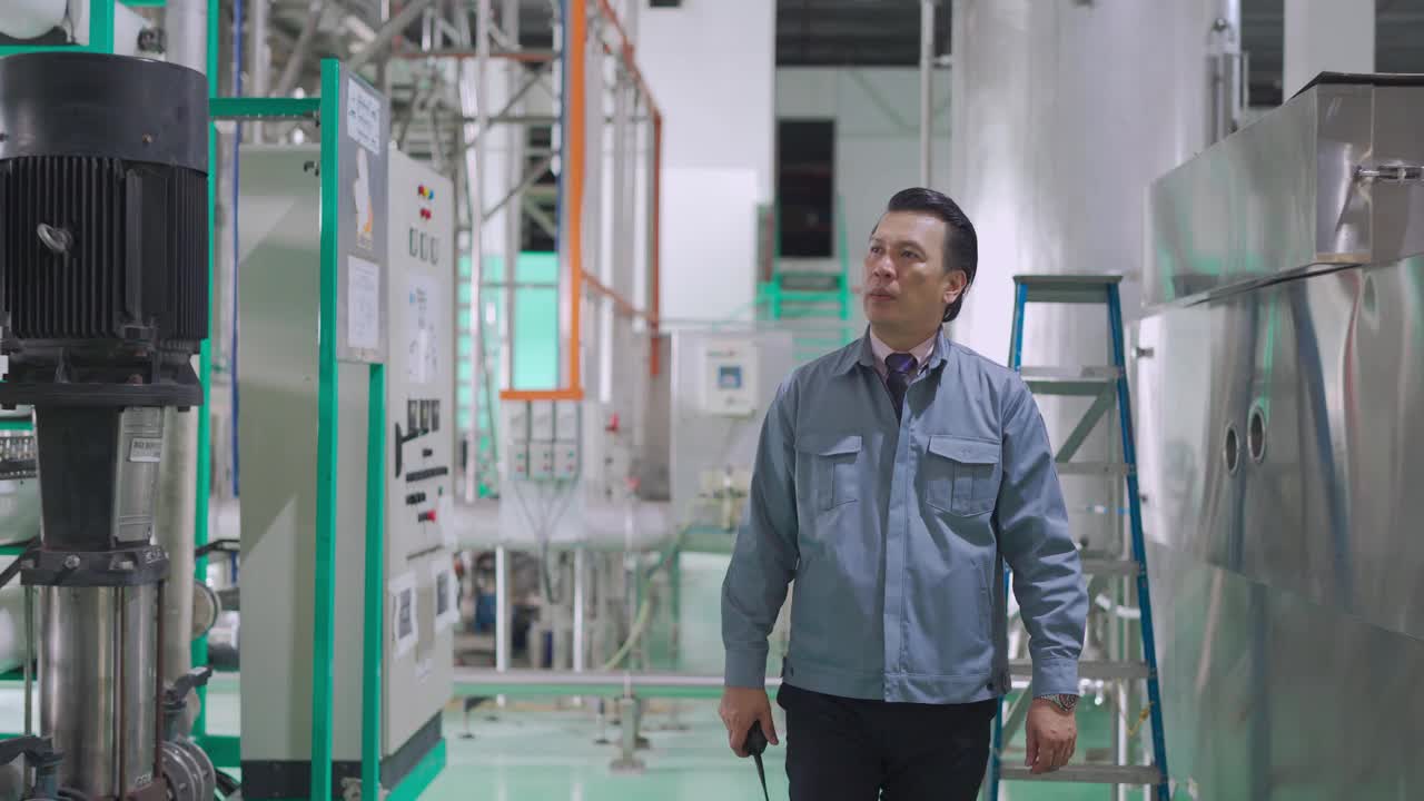 亚洲马来人成熟男性工厂经理在工厂内走动，用对讲机与同事交流视频下载