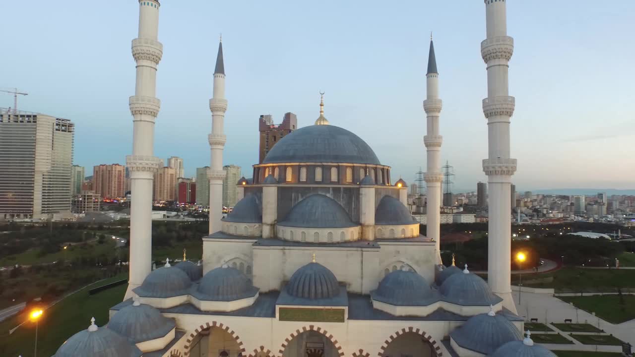 4k无人机电影观看日落和傍晚巨大的伊斯兰清真寺与拥挤的城市视图-现代和传统的伊斯兰建筑寺庙之间的摩天大楼和高速公路无人机拍摄包括近距离的尖塔和圆顶-适合斋月和eid视频下载
