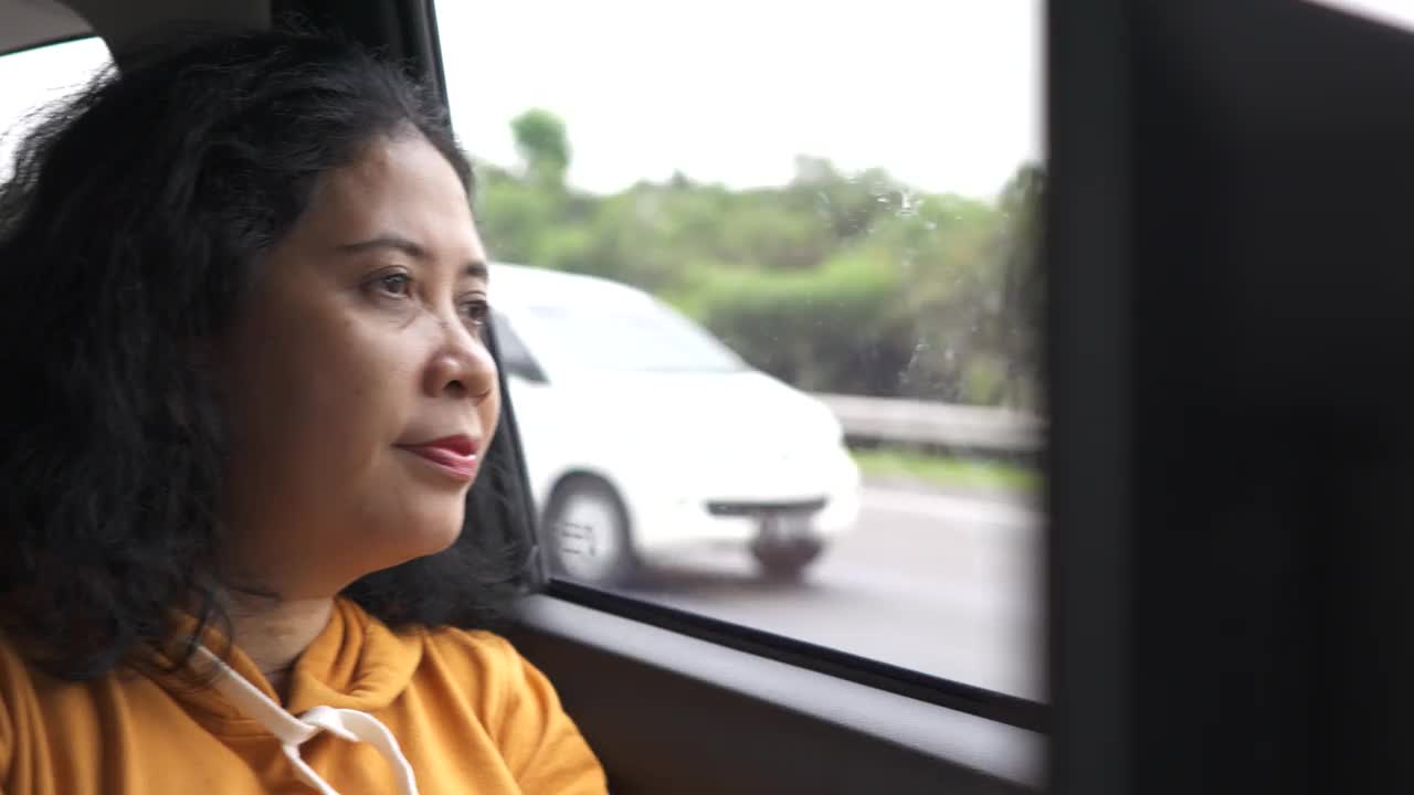 一个疲惫而忧心忡忡的女人坐在车里，看着窗外想着她的问题视频下载