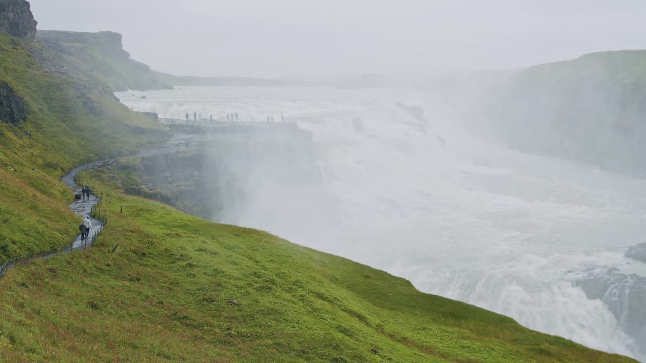 湾瀑布及游客站在观景台的剪影。冰岛全景景观视图视频素材