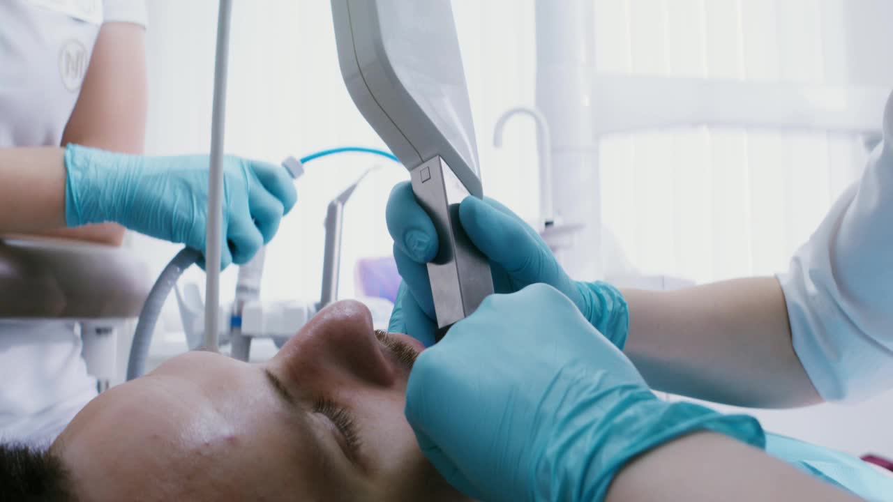 一个病人躺在牙科椅上，医生用相机检查他的牙齿视频素材