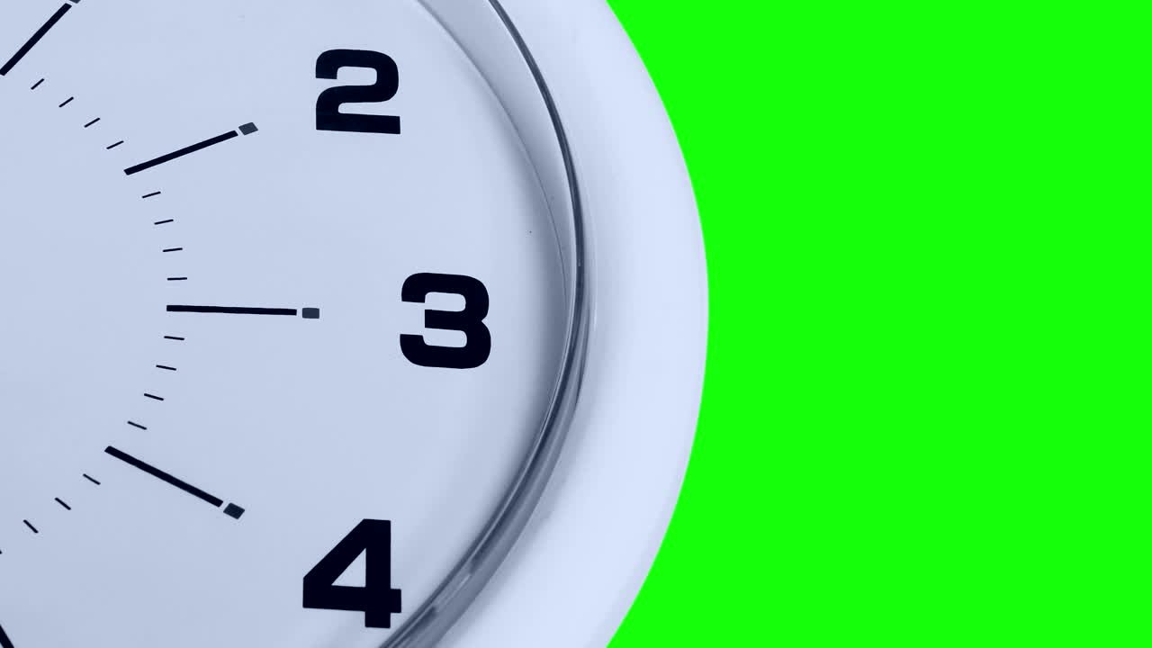 白色时钟与数字和一个滴答的箭头的特写，用绿色的屏幕背景拍摄视频素材