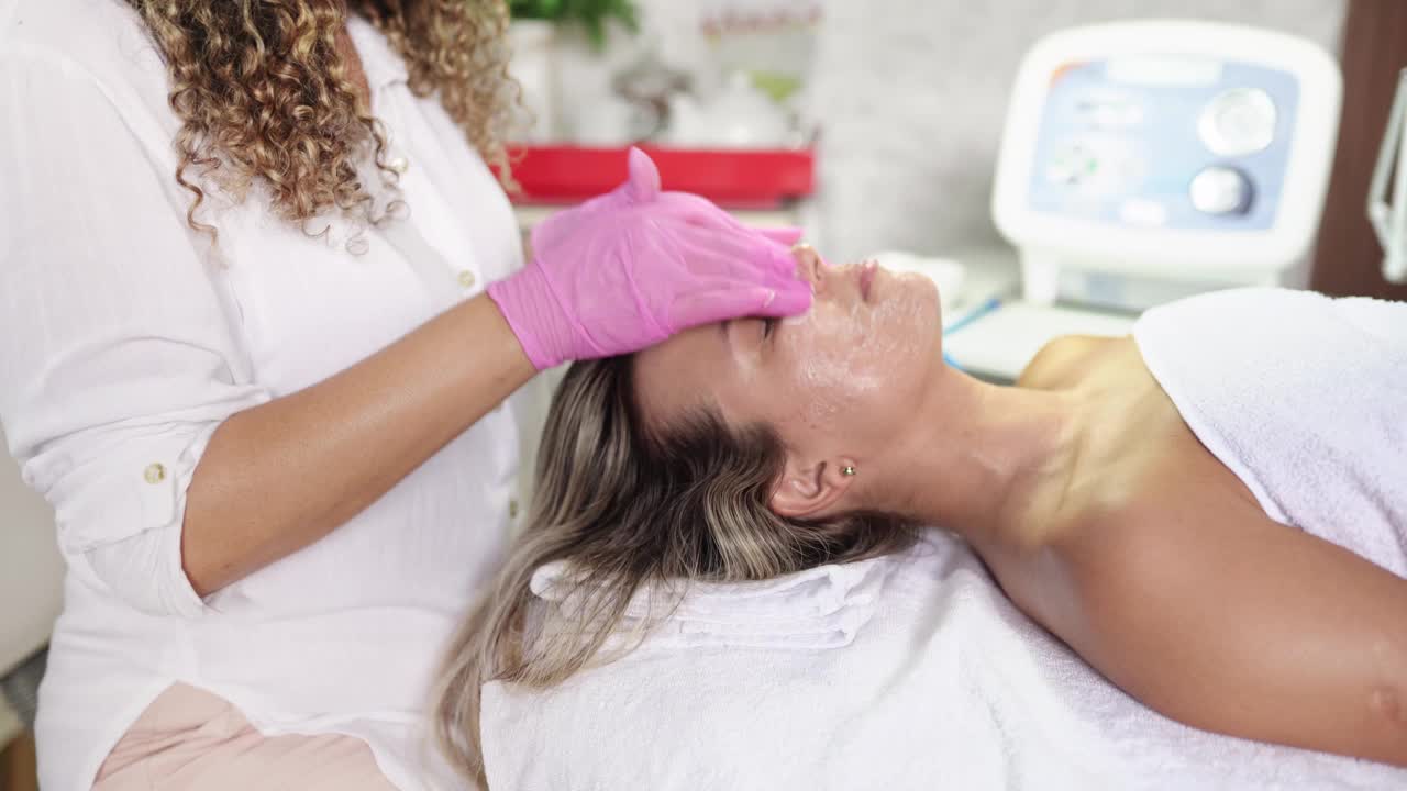 美容师在女性客户脸上按摩润肤霜视频下载