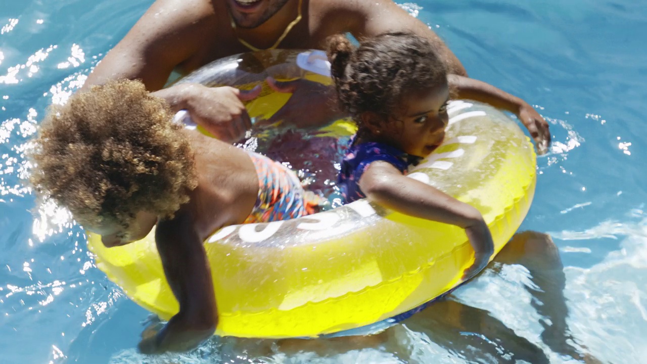 父亲和女儿在阳光明媚的夏日游泳池里玩耍视频素材