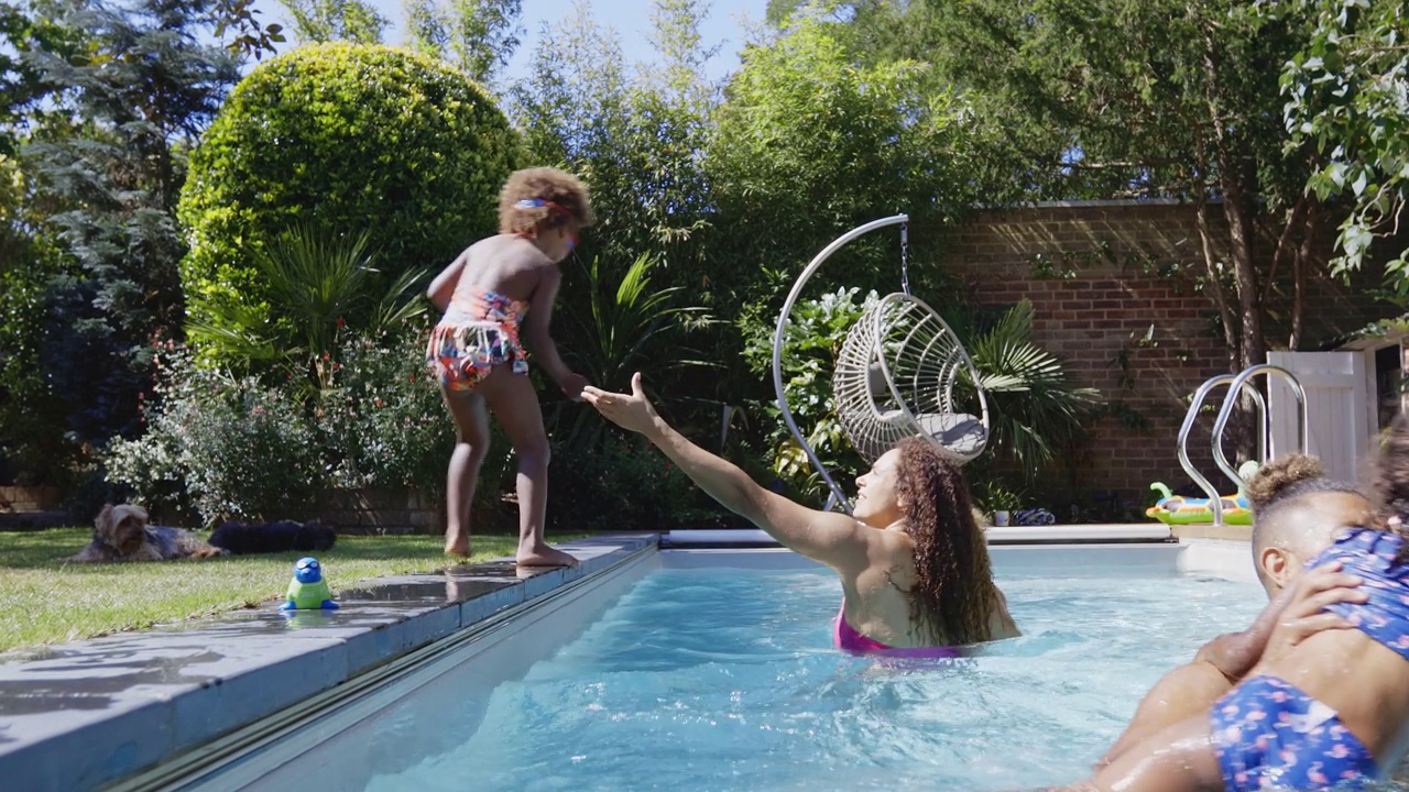 父母抓住女儿跳入阳光明媚的夏日游泳池视频素材