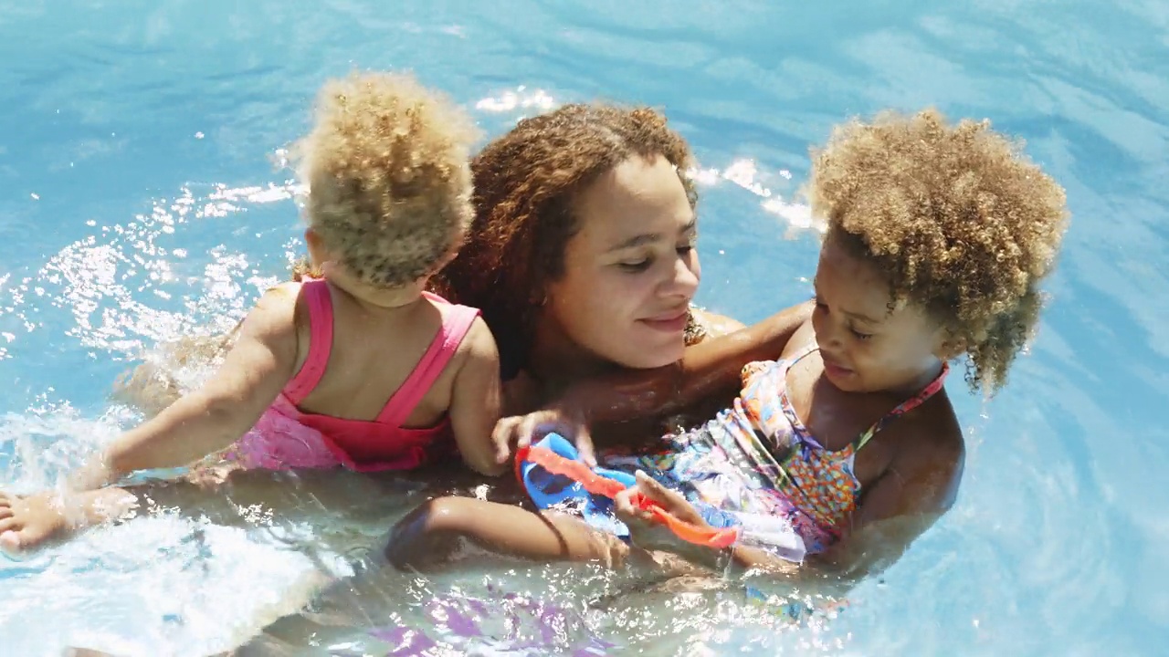 快乐的母女在阳光明媚的夏日游泳池里游泳视频素材