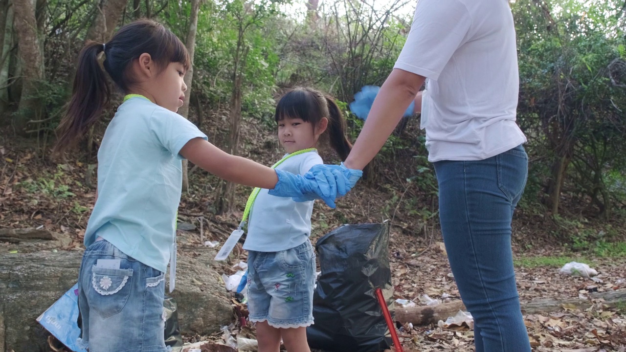 一群亚洲志愿者家庭在河边捡起垃圾。把垃圾放在垃圾箱里，帮助保护环境。世界环境日视频素材