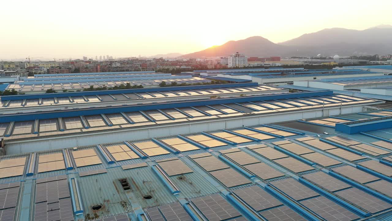 太阳落山时，太阳能电池板安装在一家大型工厂的屋顶上的航拍照片视频下载