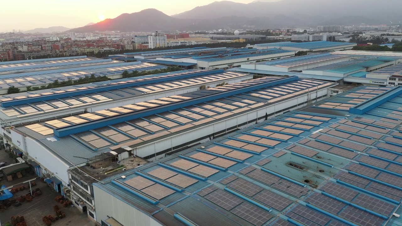 太阳落山时，太阳能电池板安装在一家大型工厂的屋顶上的航拍照片视频下载