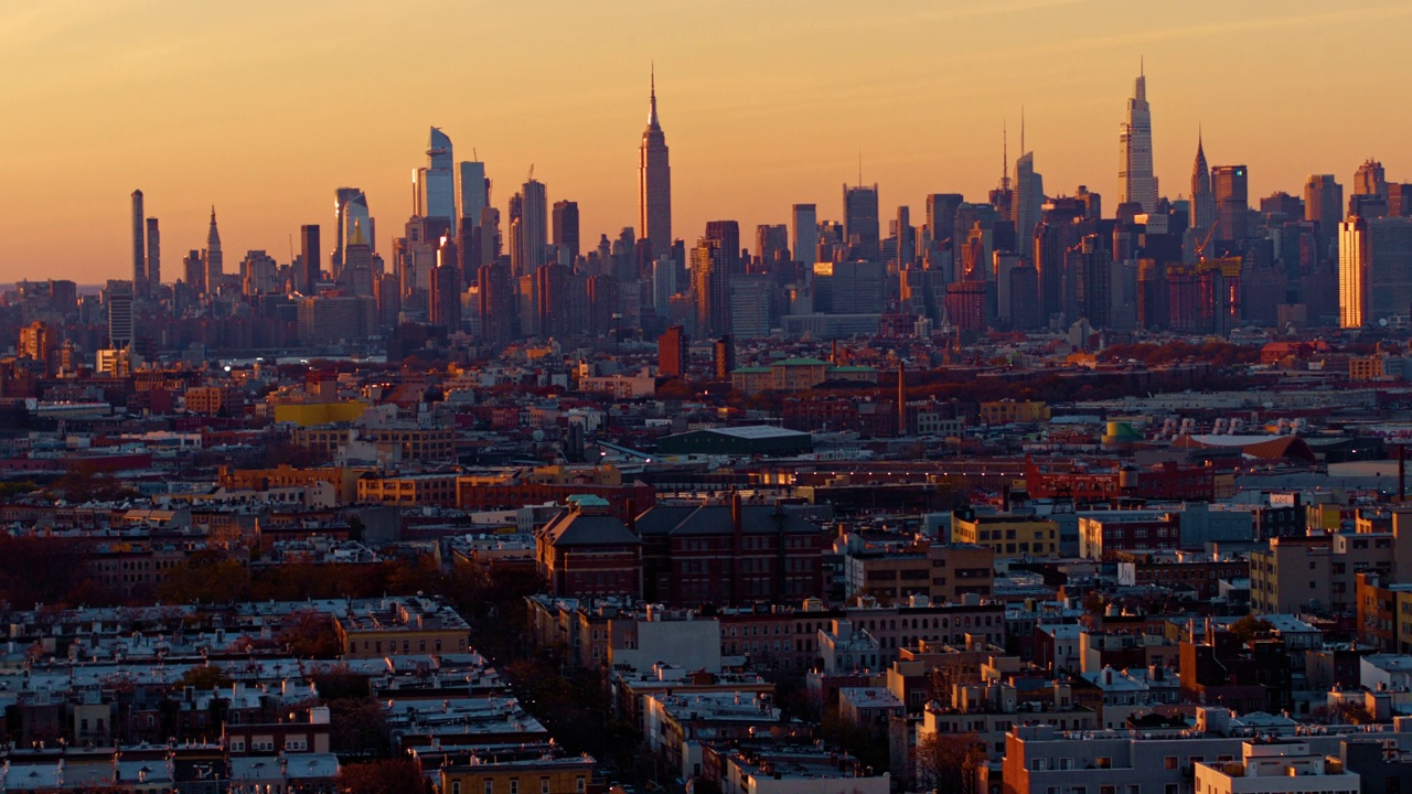 晚上的曼哈顿天际线包括哈德逊广场、帝国大厦和其他标志性建筑。俯瞰布鲁克林布什维克住宅区的远景。航拍视频与快速平移摄像机运动。视频素材