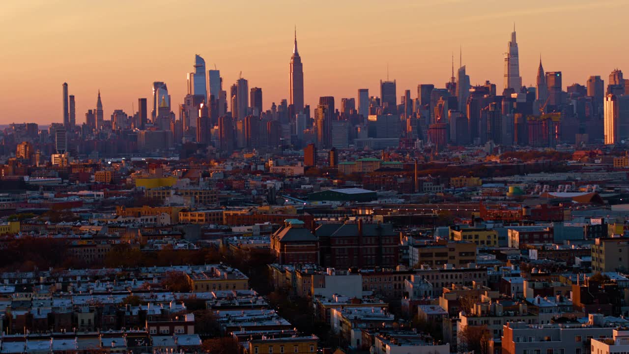 晚上的曼哈顿天际线包括哈德逊广场、帝国大厦和其他标志性建筑。俯瞰布鲁克林布什维克住宅区的远景。空中视频与平移相机运动。视频素材