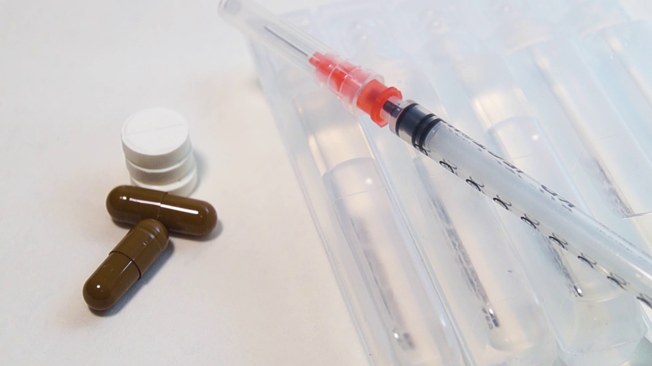 一个胰岛素注射器和药物放在安瓿上，旁边是不同的药片视频素材