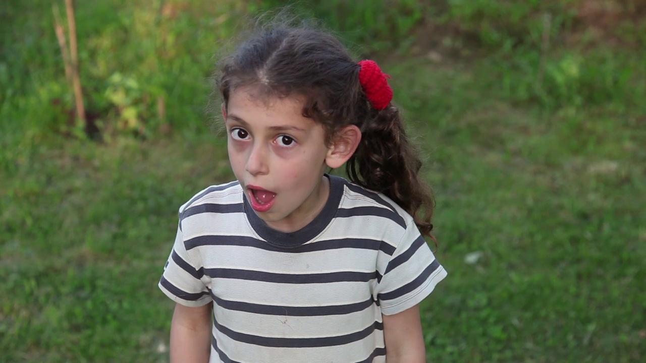 一个惊讶的小女孩在后院张着嘴的肖像视频下载