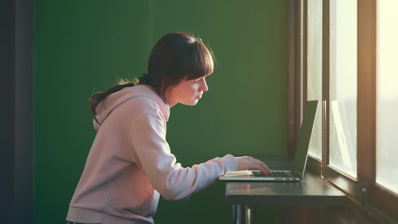 一个年轻的黑发女人坐在笔记本电脑前。听到好消息开始激动地欢呼雀跃。运气或彩票中奖的概念视频素材