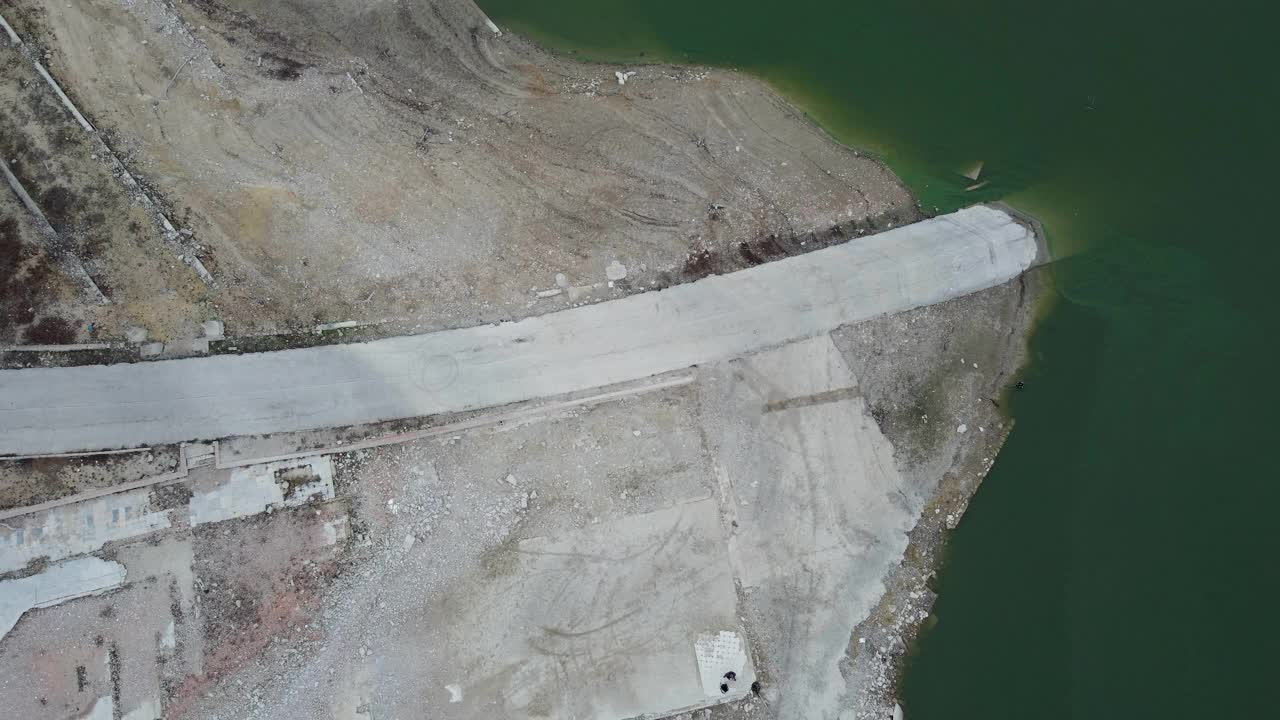 受干旱影响的水库岸线的鸟瞰图，有一条路通向岸线。视频素材