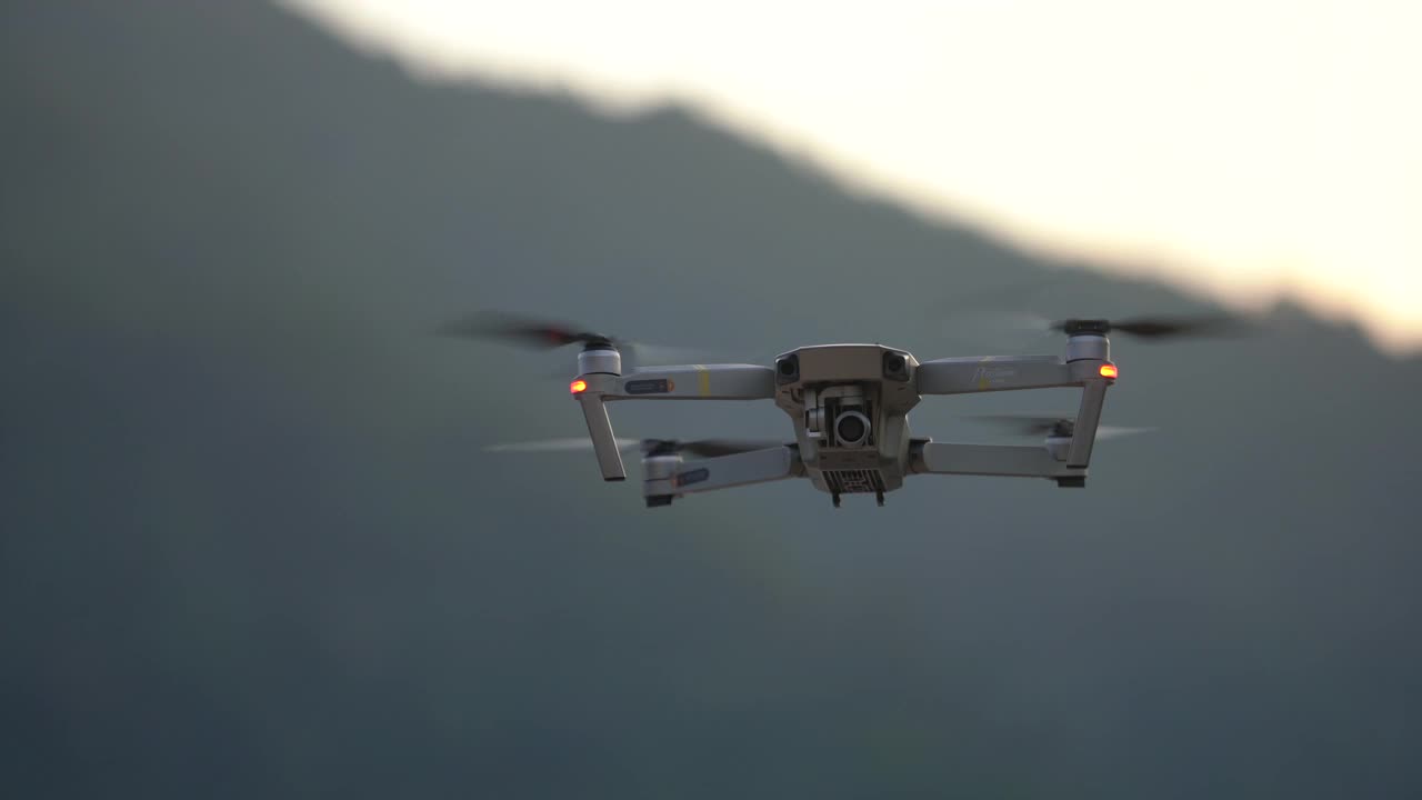 带着数码相机的四轴无人机在日落时分飞行视频下载