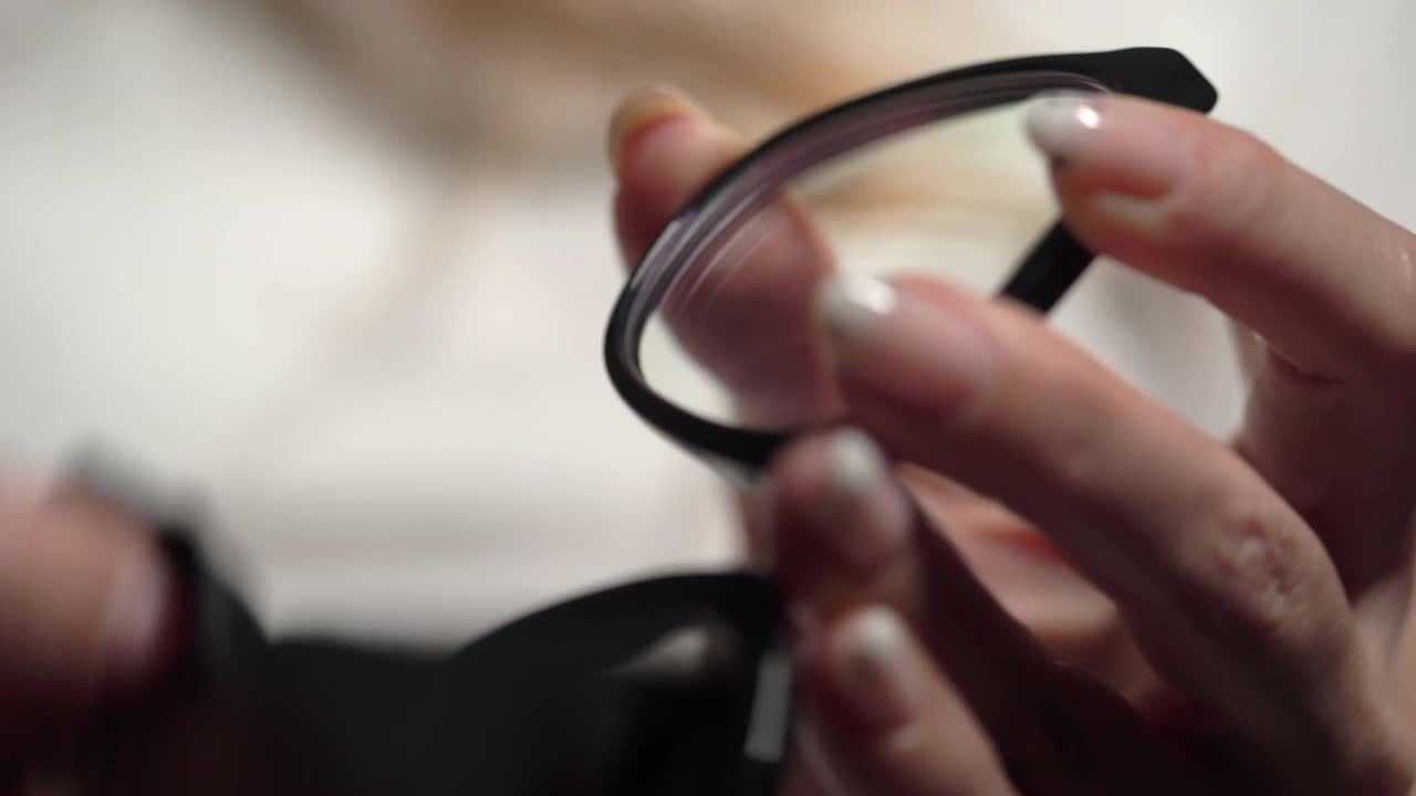女人手里拿着眼镜。女孩用纸巾擦眼镜视频下载