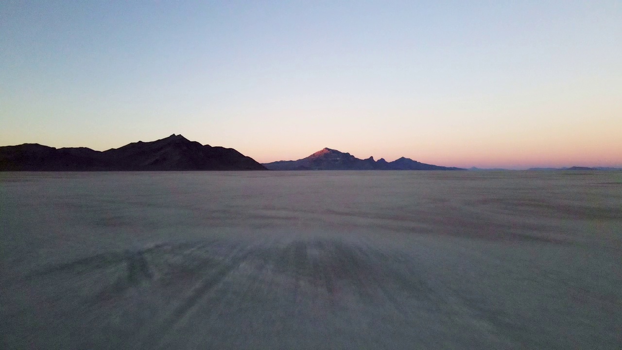 在冬天的黄昏时，向后移动的低角度无人机穿过博纳维尔盐沼视频素材
