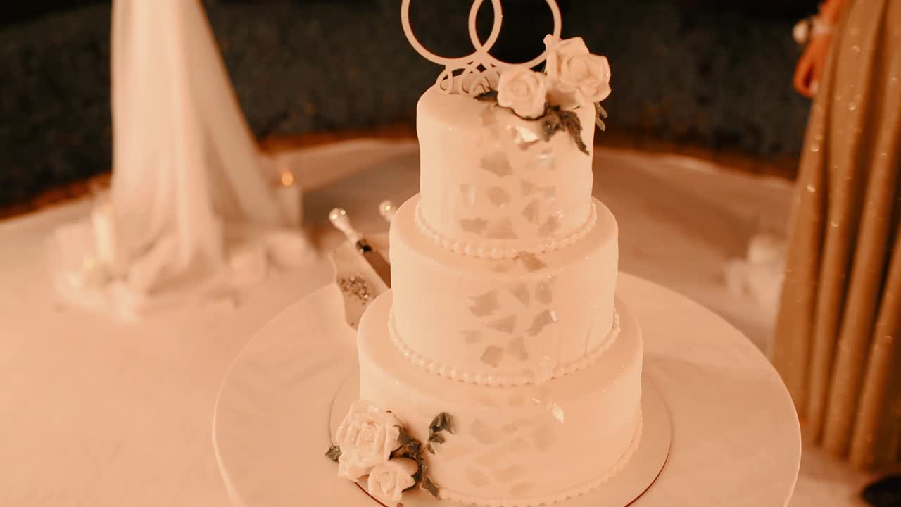 婚礼蛋糕装饰金戒指宴会厅特写。婚礼宴会用的白色蛋糕面包视频下载