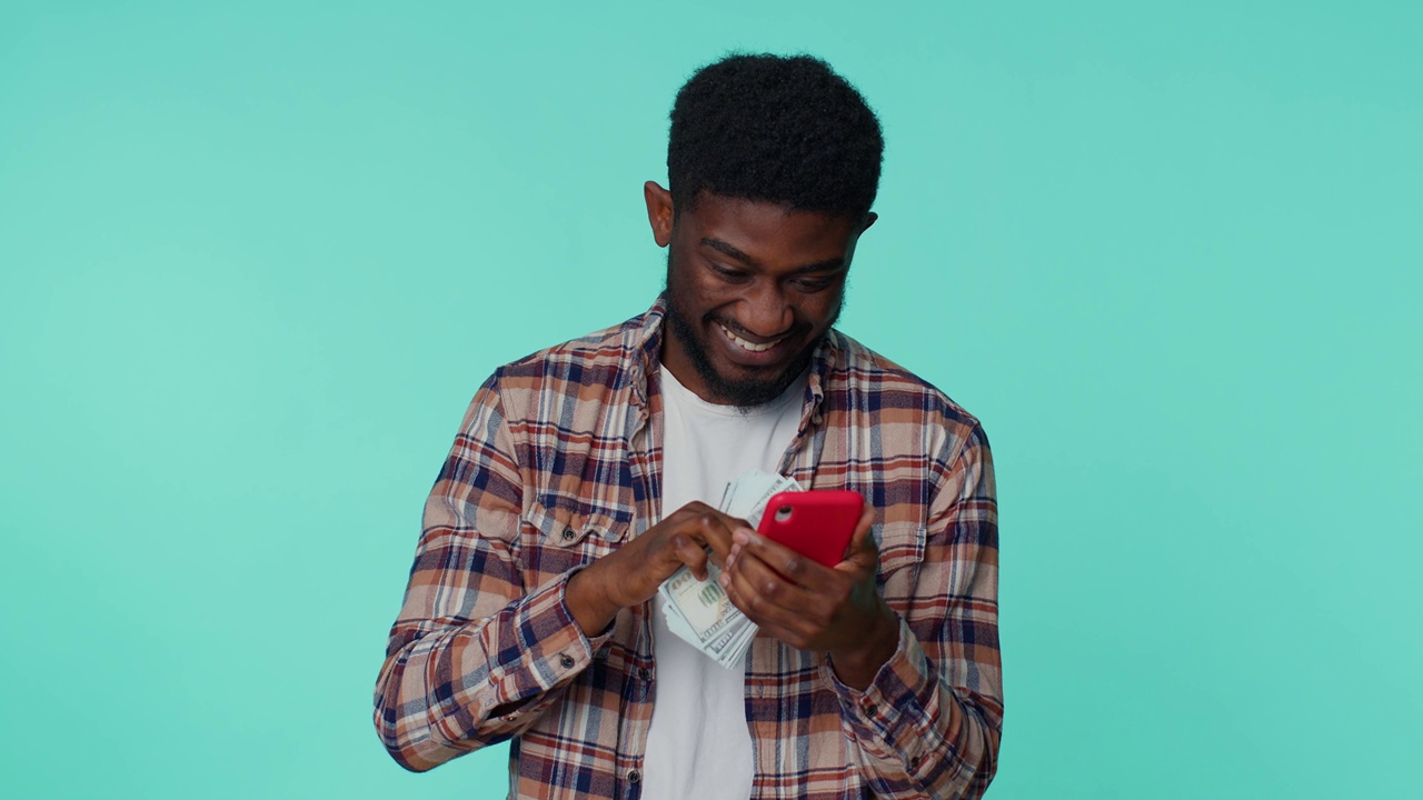 快乐的非裔美国人手机显示真心欢喜赢，收钱美元现金视频素材