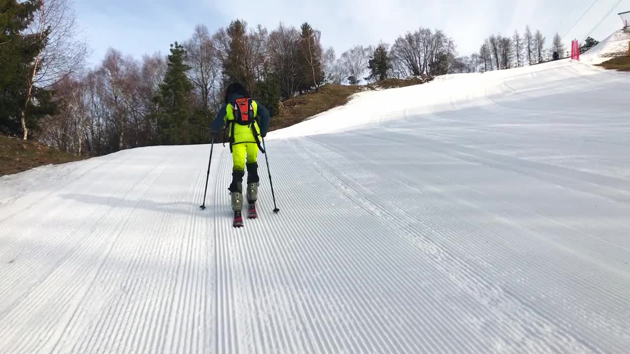 一个小的滑雪登山者在滑雪斜坡上攀登视频下载