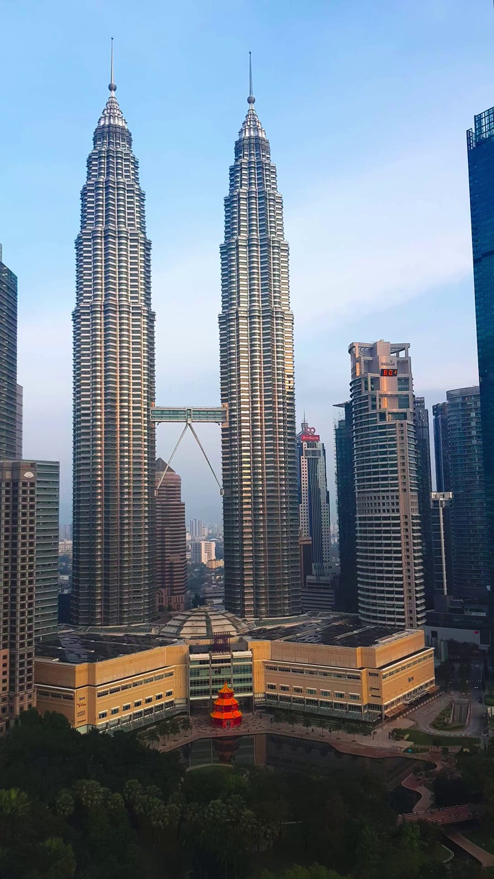 垂直镜头现代独特的建筑Petronas双子塔(KLCC)和周围的日出时间视频下载