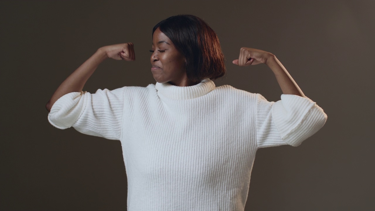 酷的骄傲的非洲裔美国女人展示二头肌，做肌肉手势。女孩的力量。个人的成就。ProRes编解码器视频下载