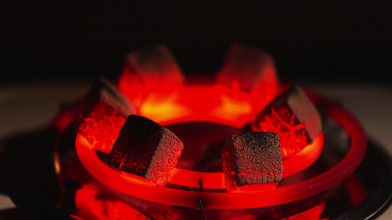 烧红煤块做水烟，用电加热器加热，在家里准备水烟，灰烬，黑暗的室内视频下载