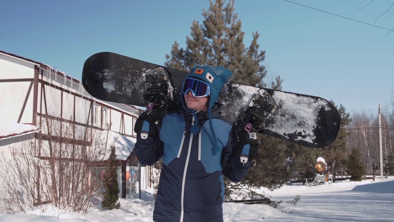 一个肩膀上扛着滑雪板的快乐小伙子，随着音乐举起双手视频下载