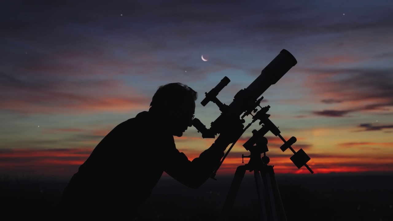 一个男人的剪影，望远镜和夜空下的乡村。视频下载
