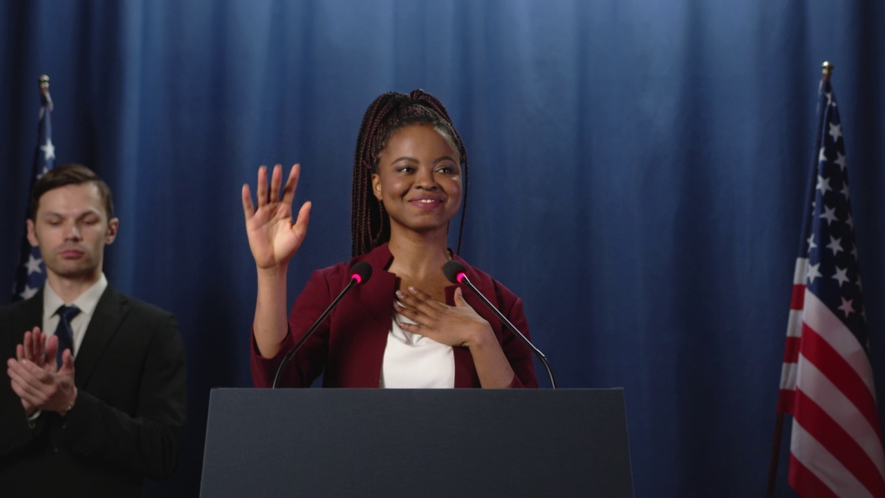 在演讲结束后，身穿红色夹克的年轻黑人女政治家向观众致谢视频下载
