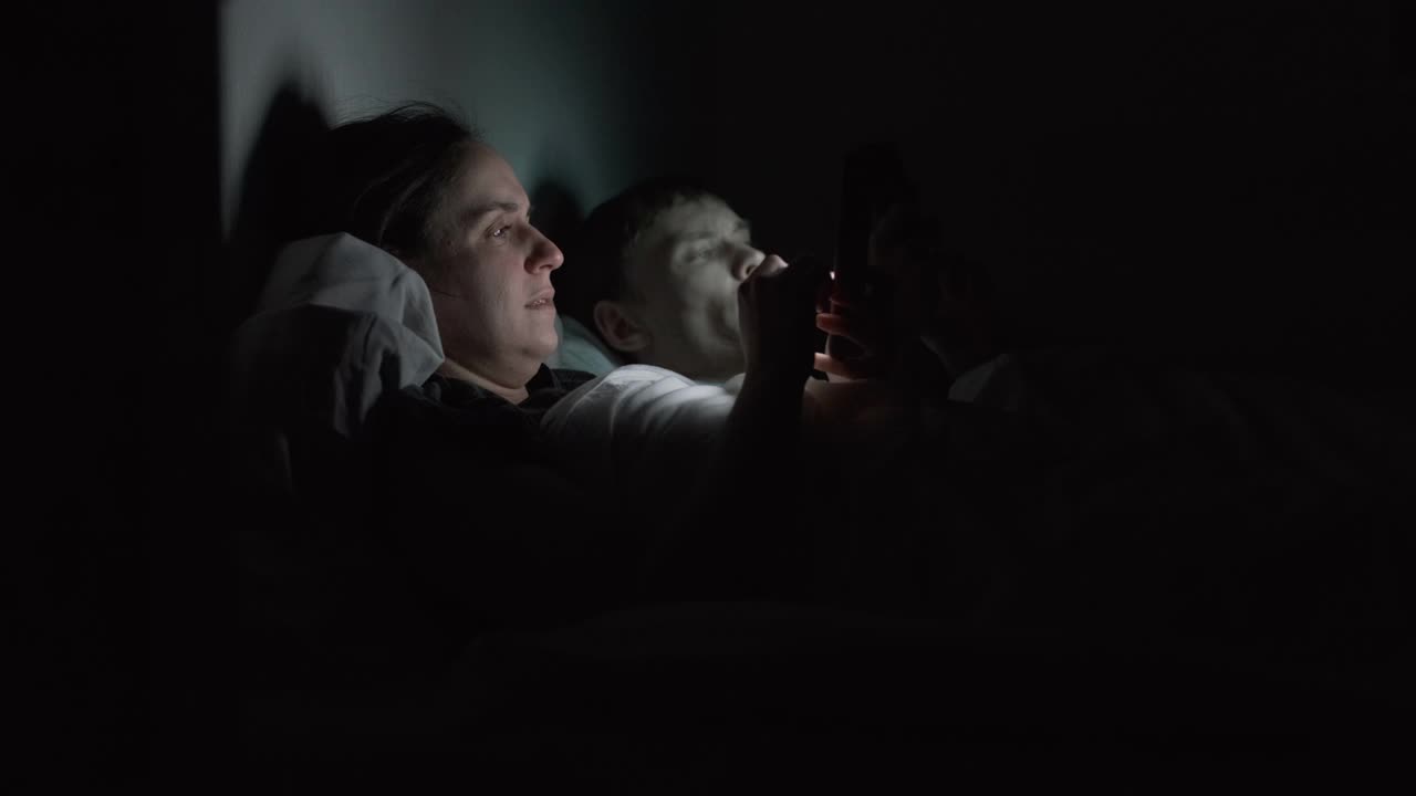夫妻在晚上使用智能手机的侧视图视频素材