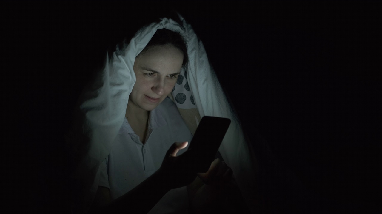 女人在毯子下使用智能手机视频素材