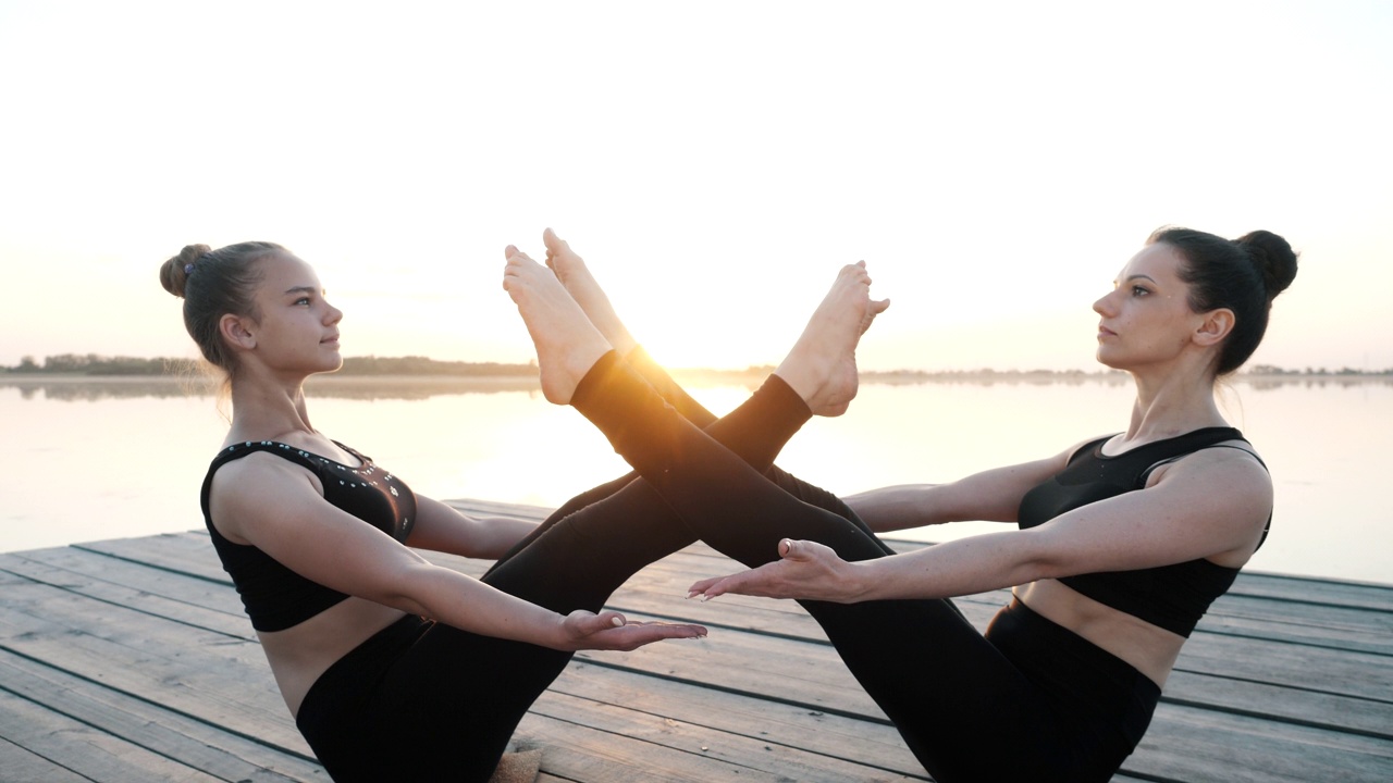 两个坐着的女性身体做双人瑜伽体位，一起做练习体位视频素材