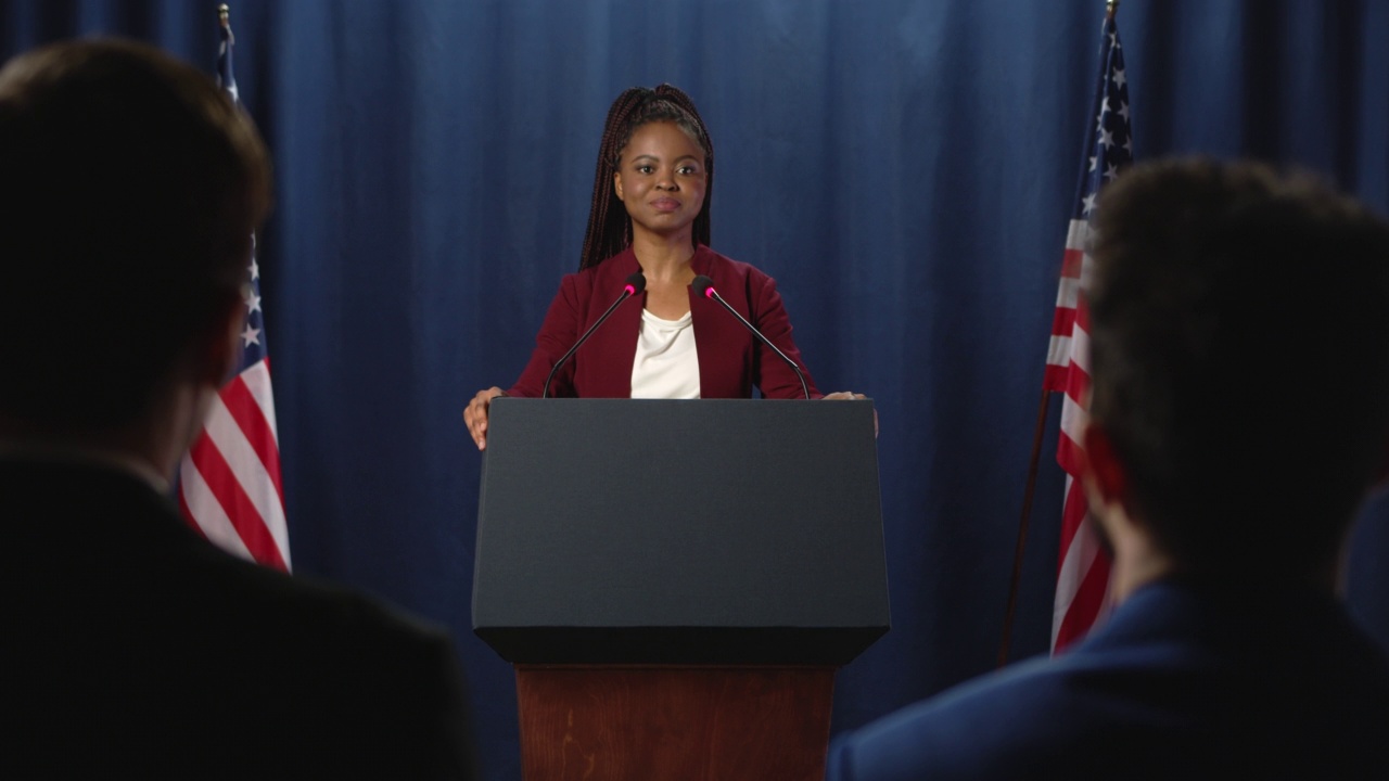 在演讲结束后，一位身穿红色夹克的年轻黑人女性政治演讲者正在回答问题视频下载