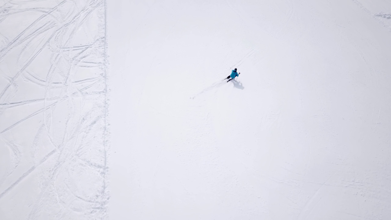 4k航拍，无人机在滑雪区域的滑雪斜坡上跟踪滑雪者。滑雪者在冬季的高山滑雪坡上滑雪，鸟瞰阿尔卑斯山视频素材