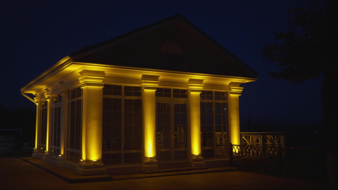 有柱子的有顶阳台在晚上被灯光照亮。视频下载