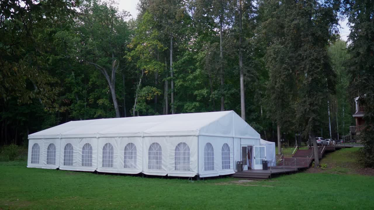 一个白色的节日帐篷在夏日的森林中搭建视频下载