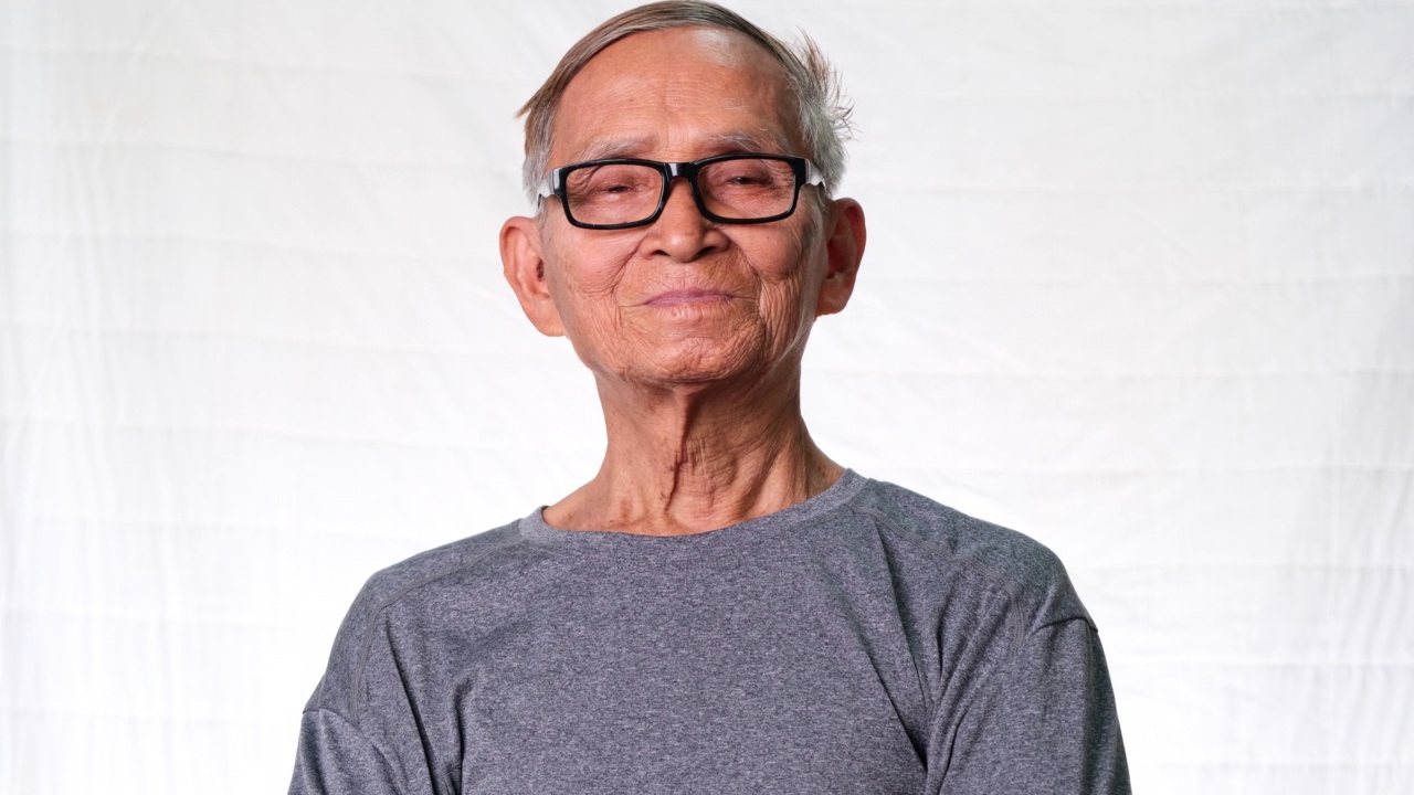 亚洲老人在家里开心地微笑。一位快乐的老人享受着他的退休生活，在室内看着镜头。视频素材