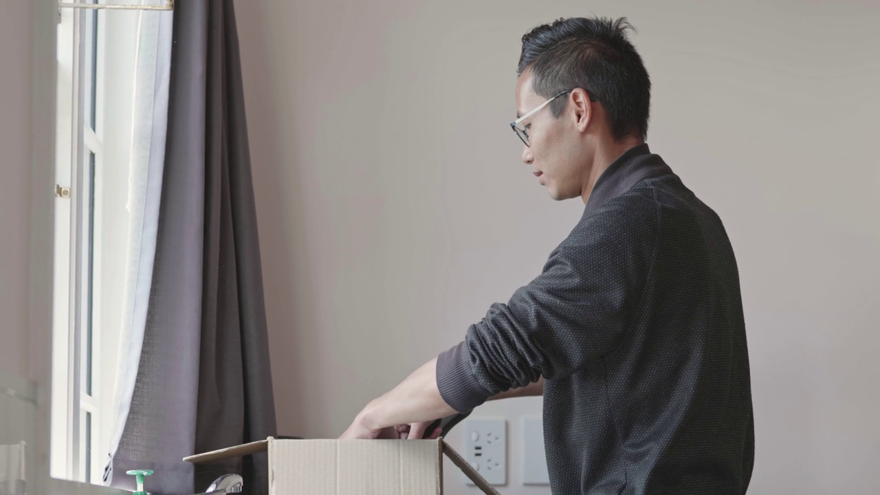 一名亚洲男子在他的新房子里打开厨房用具视频下载
