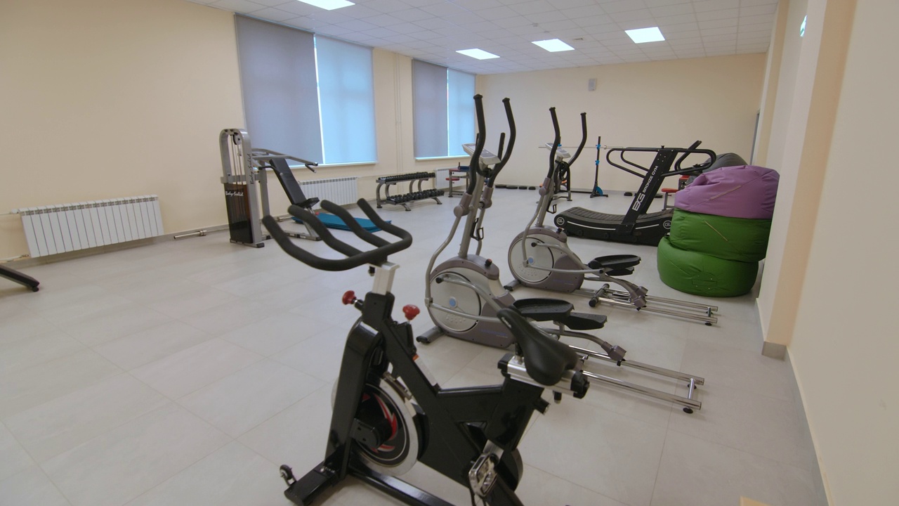 在明亮宽敞的健身房里，一排机器靠墙而立视频素材