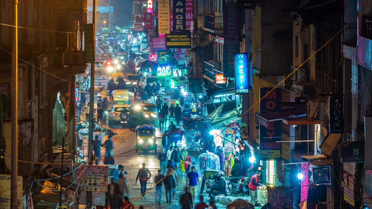 时间推移的主要集市街道显示霓虹灯招牌，商店，交通和行人在夜间在德里中心，印度，缩小视频素材