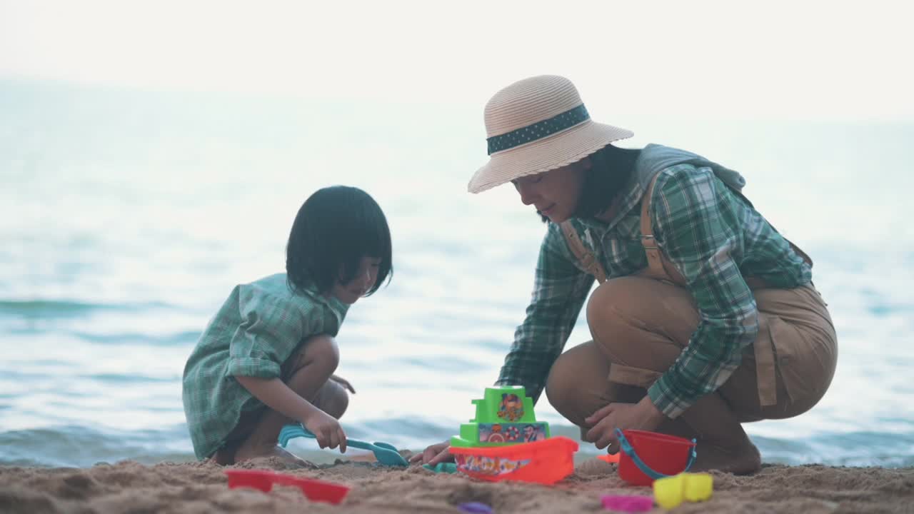 亚洲妈妈和儿子在海滩上玩玩具视频素材