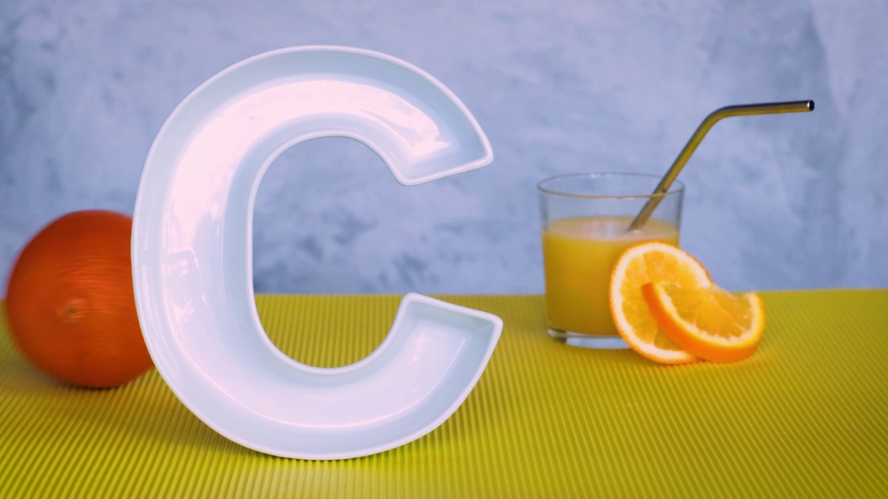 维生素C在食品中的概念。字母C形状的盘子，鲜榨橙汁和两个滚动的橙子。抗坏血酸对免疫系统功能很重要。循环录像。视频下载